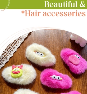 Detailed close-up of plush hair clips with cartoon big eyes on a rustic wooden background