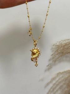 Detail of 18k gold plated unicorn pendant necklace with white zircon and star charms