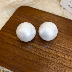 Dettaglio di orecchini di perle vintage con finitura opaca su supporto di legno