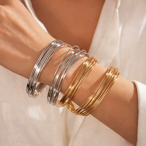 Minimalist twisted geometric metal bangle in gold and silver finish on wrist