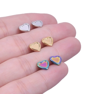 Macro detail of heart-shaped stainless steel stud earrings in silver, gold, and rainbow finish