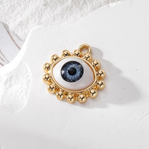 Blue evil eye charm with gold trim and crystal accents on a white stone background