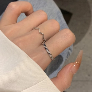 Detailed view of a silver wave twisted ring with inlaid cubic zirconia on a model hand