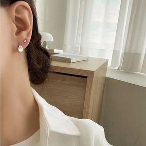 Minimalist 925 sterling silver shell earrings and pearl studs worn by a model