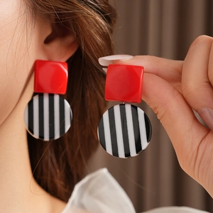 Detail showing vintage resin earrings with red square studs and striped circular drops