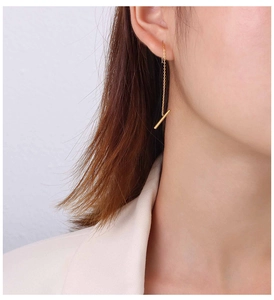 Detail view of 18k gold minimalist linear drop earring on model showcasing long bar chain