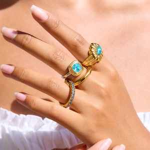Close-up of stacked gold and silver rings with light blue zircons on model fingers