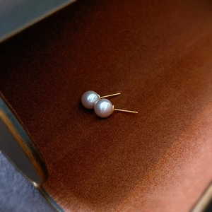 Macro shot of elegant lavender pearls and golden metal studs on a textured background