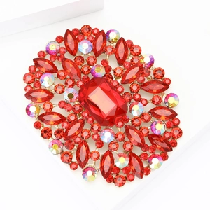 Elegant gold alloy brooch with large red crystal and colorful accents on white stand