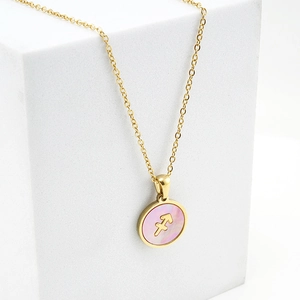 Détail macro du collier Sagittaire doré avec incrustation de nacre rose sur blanc