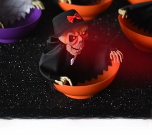 Macro shot of Halloween skeleton fruit plate with glowing red LED eyes and black cloak