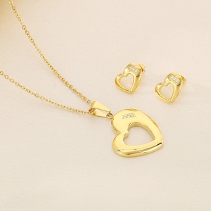 Gold hollow heart jewelry set with necklace and earrings on minimalist beige fabric