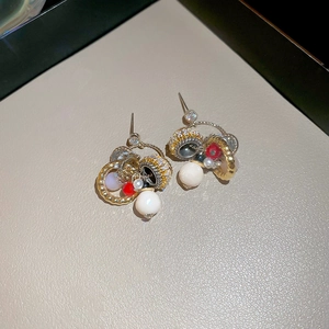 Detailed macro view of vintage gold earrings with pearls and red beads on leather background