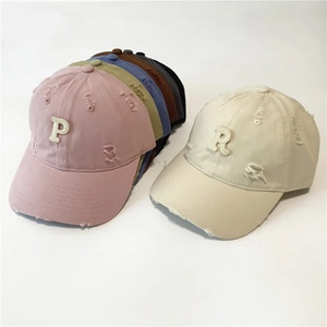 Detailansicht der Baumwoll-Baseballkappen mit Löchern im Distressed-Look und Patches