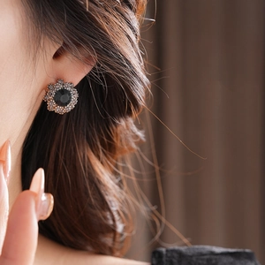 Close-up of vintage flower stud earring with black stone and diamonds on model
