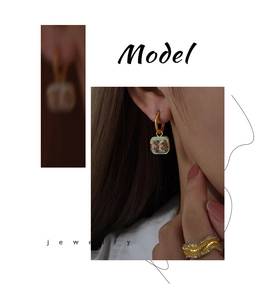 Detail of square zircon pendant earrings and wavy gold ring set on a model