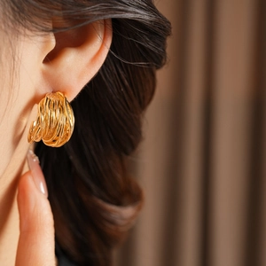 Primo piano di eleganti orecchini a cerchio placcati in oro a più strati su una modella