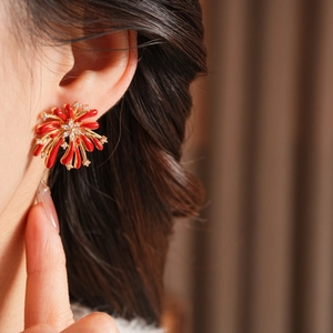 Détail de boucles d'oreilles feu d'artifice en émail rouge et zircons sur or