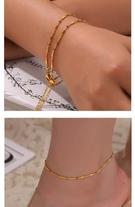 Detail of gold thin chain bracelet and anklet with colorful beads on wrist and ankle