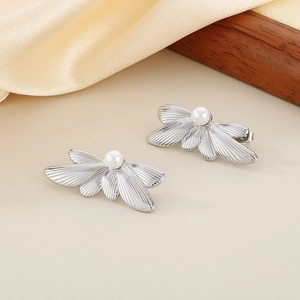 Detail of silver butterfly earring with white pearl on silk fabric and wood decor
