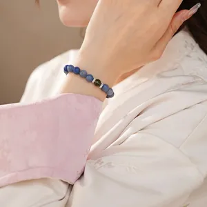 Elegant beaded bracelet with blue crystals and green bead shown on a model's wrist