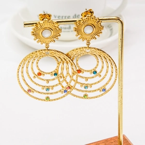 Macro detail of Bohemian gold hoop earrings with multi-colored gemstones and sunburst studs