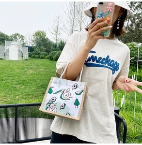 Detail of canvas tote bag with avocado cartoon print and jute bottom in outdoor garden