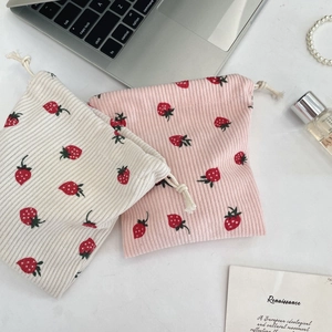 Detail of corduroy drawstring pouches with red strawberry prints for cosmetics storage