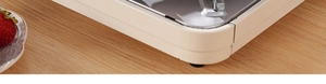 Detail of non-slip rubber feet on beige egg roll maker over a wooden tabletop