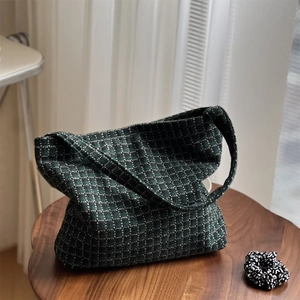 Detail of green and black plaid wool shoulder bag on a vintage wooden table setting