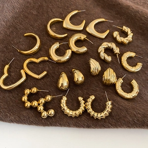 Detailed display of polished gold geometric earring set on dark textured fabric background