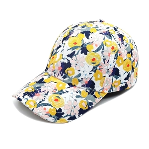 Détail d'une casquette de baseball à fleurs jaunes et bleues sur fond blanc