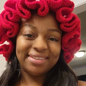 Detail shot of a red knitted beanie featuring tiered ruffle edges and wavy layered design