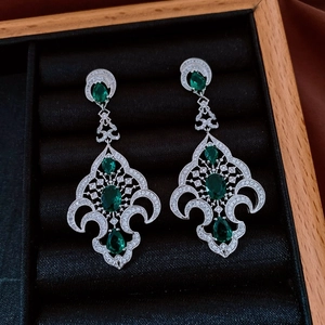 Détail de boucles d'oreilles vintage en argent avec pierres vertes en écrin de velours
