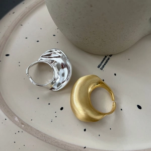 Minimalistische geborstelde gouden en zilveren open ringen op een keramisch bord