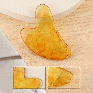 Translucent heart-shaped amber resin gua sha board for facial massage with smooth texture