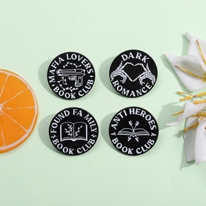 Set of four black circular enamel book club pins with white literary theme designs