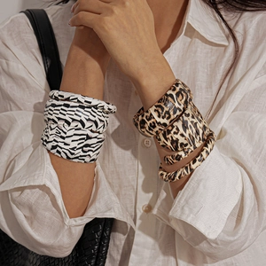 Close-up of zebra and leopard print wrap bracelets on model wearing a white linen shirt