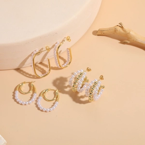 Detailed view of three luxury pearl earrings on stone pedestals in gold finish