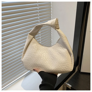 Close-up of cream woven leather texture and crescent shape on minimalist shoulder bag