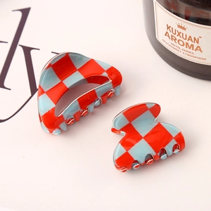 Detail view of large and small checkered hair claws in red and blue acetate-like finish