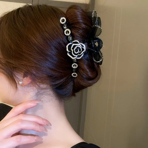 Détail de la pince à cheveux camélia avec nœud en maille noire et strass brillants