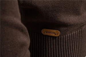 Gros plan détaillé du pull en maille marron avec écusson en cuir et ourlet côtelé