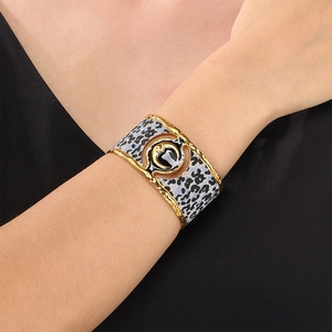 Macro detail of wide gold bangle featuring leopard print finish and crescent moon relief