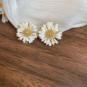 Detailed view of daisy stud earrings featuring white petals and golden floral centers