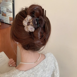 Détail d'une pince à cheveux fleurie en peluche sur un chignon élégant de dos