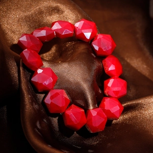 Detail of red faceted crystal beads on a bohemian style stainless steel bracelet