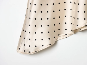 Détail d'une robe en satin champagne à pois noirs montrant la finesse des coutures