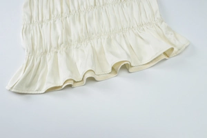 Detailed view of beige chiffon dress hem featuring pleated textures and ruffle design