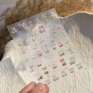 Macro detail of ta-383 nail stickers with gold embossed cherries and angel motifs